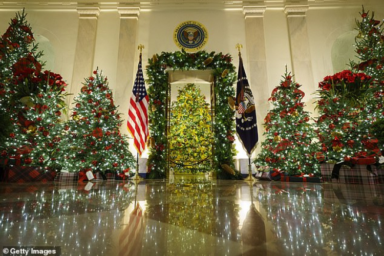 The Official White House Christmas Tree sits in the Cross Hall and Blue Room as the focus of the holiday decorations - it has bright yellow ribbons in contrast with the red ribbons on the rest of the trees